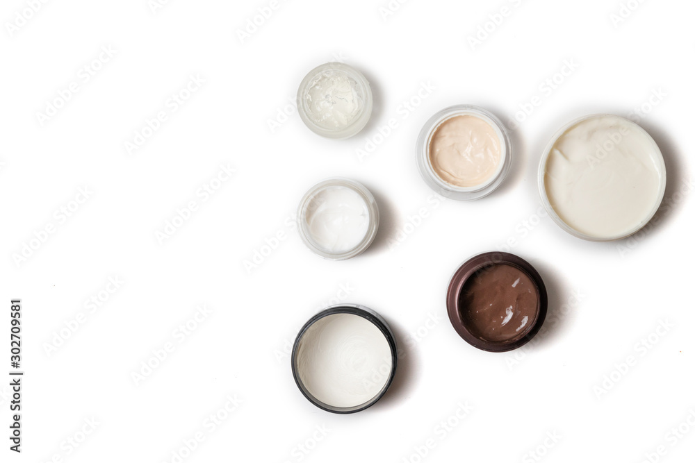 Care products for face, hands and body. Cream in jars on white background. Space for text