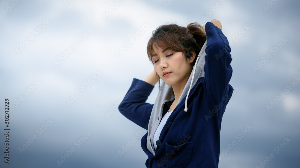 Beautiful sport asain woman standing on the rooftop of a skyscraper over a city with cloudy sky background Beautiful sport asain woman standing on the rooftop of a skyscraper over a city with cloudy sky background