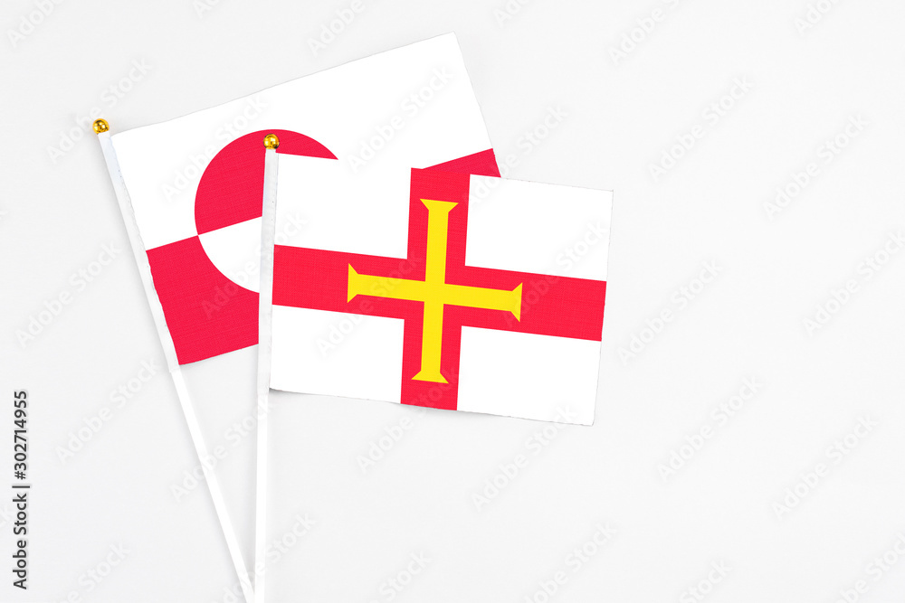 Guernsey and Greenland stick flags on white background. High quality fabric, miniature national flag. Peaceful global concept.White floor for copy space.