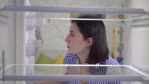 young woman looks into the empty refrigerator
