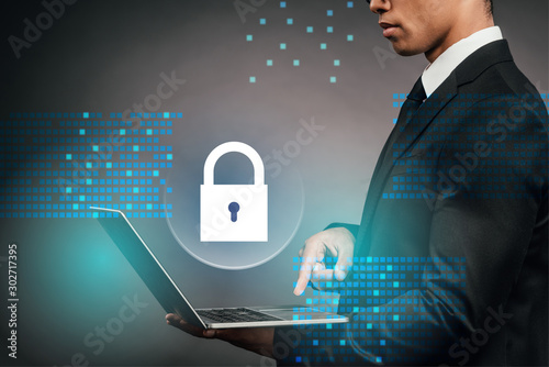 Valokuva partial view of african american businessman using laptop on dark background wit
