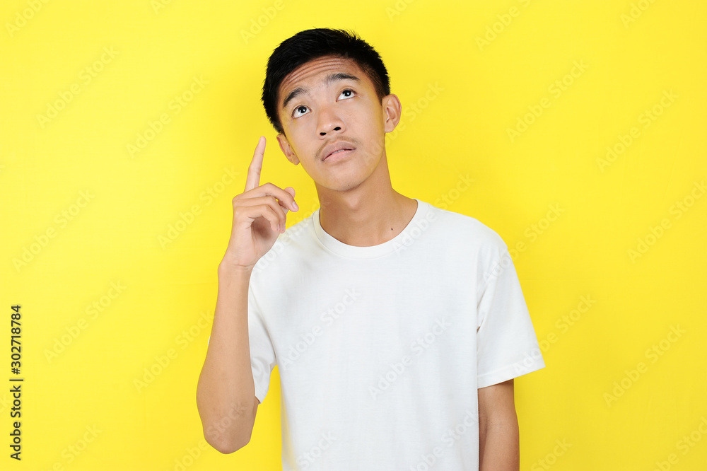 Portrait of smart young Asian man thinking and look up. Smart young Asian man wearing white t-shirt thinking and look up Portrait of smart young Asian man thinking and look up. Smart young Asian man wearing white t-shirt thinking and look up