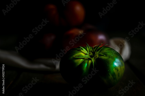 Green tomato. Black background. Moody food photography photo