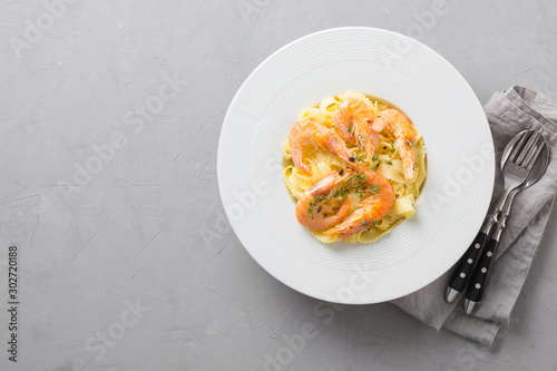 Pasta spaghetti reginelle with seafood, shrimps white plate on gray stone table, view from above. Traditional dish in Italian. Space for text. photo