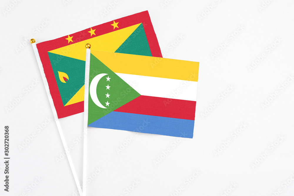 Fototapeta premium Comoros and Grenada stick flags on white background. High quality fabric, miniature national flag. Peaceful global concept.White floor for copy space.