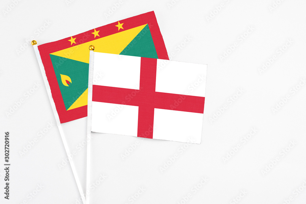 England and Grenada stick flags on white background. High quality fabric, miniature national flag. Peaceful global concept.White floor for copy space.