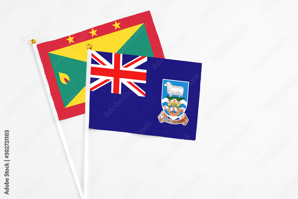 Fototapeta premium Falkland Islands and Grenada stick flags on white background. High quality fabric, miniature national flag. Peaceful global concept.White floor for copy space.
