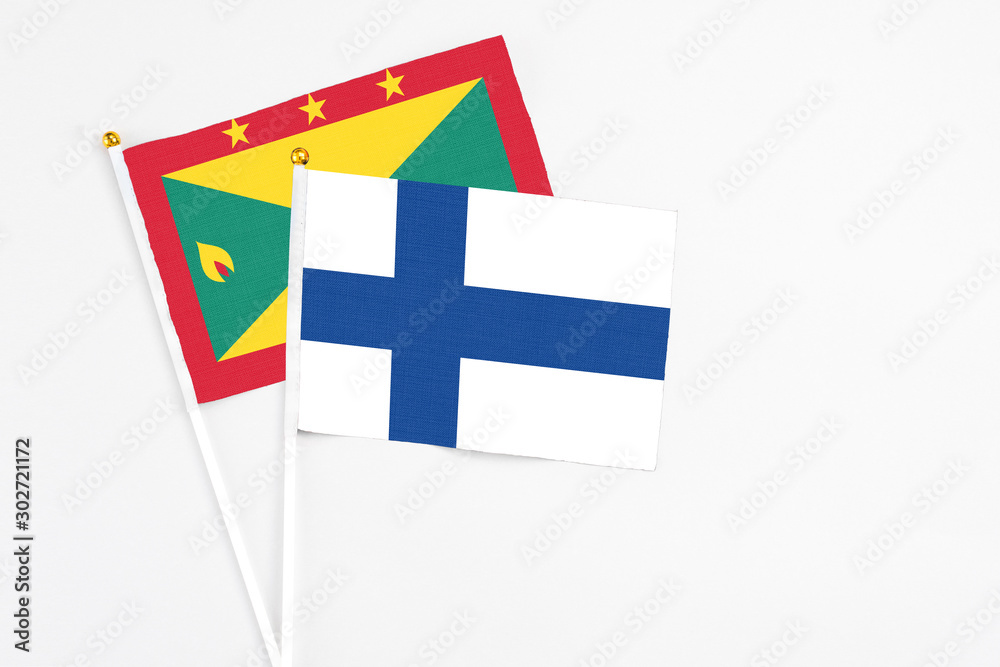 Finland and Grenada stick flags on white background. High quality fabric, miniature national flag. Peaceful global concept.White floor for copy space.