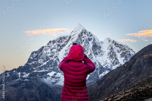 A woman from the back photographying sunrise on the Taweche mountain from Chukhung on the 3 passes trek in Nepal photo