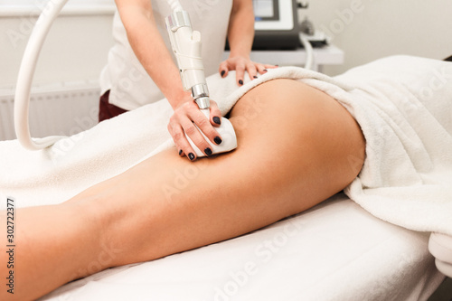 Doctor cosmetologist with a roller in his hands makes a buttocks massage with device closeup
