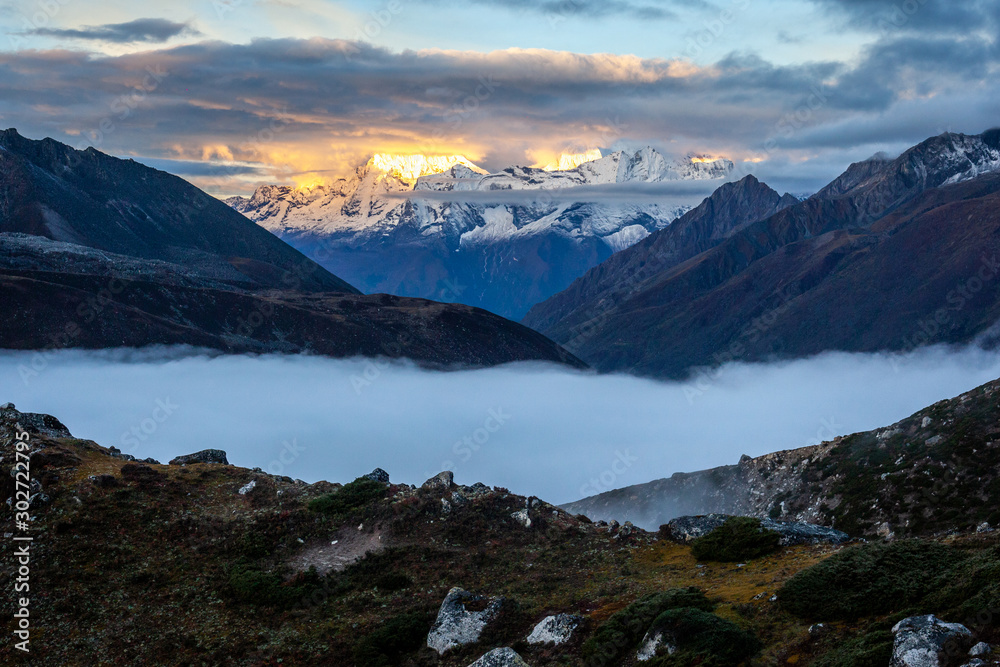 sunrise lighting mountain peaks of the himalaya with clouds under in Chukhung on the 3 passes trek