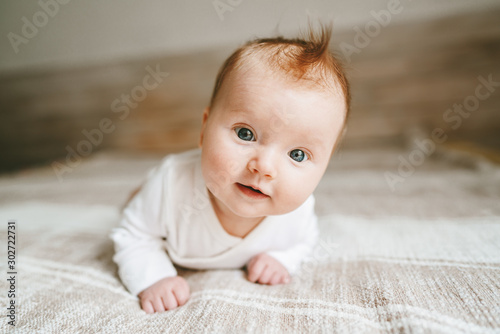 Cute baby ginger hair close up crawling on bed smiling adorable kid portrait family lifestyle 3 month old child photo