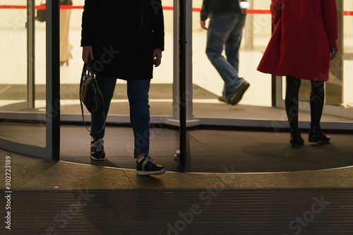 Some business persons leaving the office building, some coming. Revolving door and men' and women' feet photography. Urban office lifestyles in the end of day.