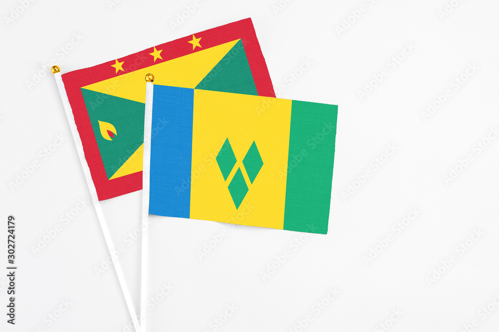 Saint Vincent And The Grenadines and Grenada stick flags on white background. High quality fabric, miniature national flag. Peaceful global concept.White floor for copy space. Saint Vincent And The Grenadines and Grenada stick flags on white background. High quality fabric, miniature national flag. Peaceful global concept.White floor for copy space.
