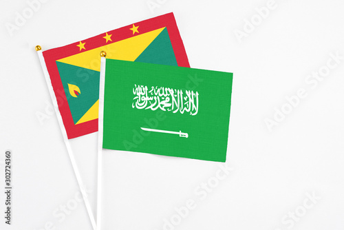 Saudi Arabia and Grenada stick flags on white background. High quality fabric, miniature national flag. Peaceful global concept.White floor for copy space.