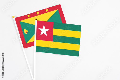 Togo and Grenada stick flags on white background. High quality fabric  miniature national flag. Peaceful global concept.White floor for copy space.