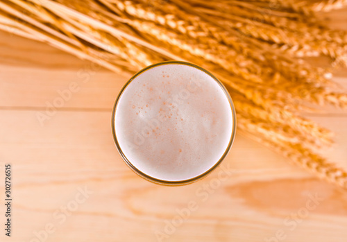 Glass of beer with wheat ears on a wooden background. Top view.