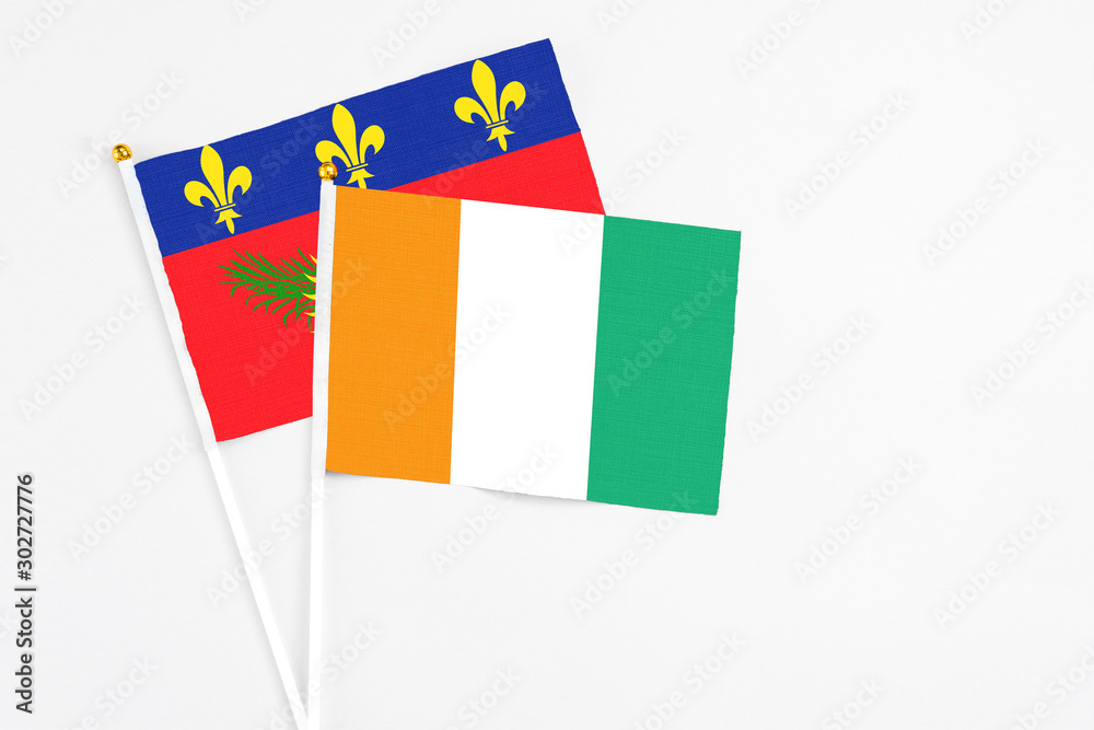 Cote D'Ivoire and Guadeloupe stick flags on white background. High quality fabric, miniature national flag. Peaceful global concept.White floor for copy space. Cote D'Ivoire and Guadeloupe stick flags on white background. High quality fabric, miniature national flag. Peaceful global concept.White floor for copy space.