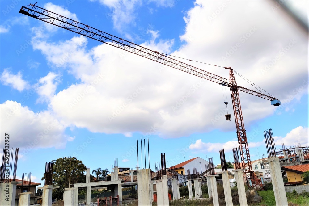 Crane and building construction site against blue sky with white clouds