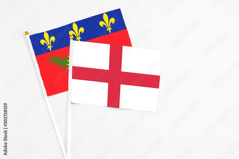 England and Guadeloupe stick flags on white background. High quality fabric, miniature national flag. Peaceful global concept.White floor for copy space.