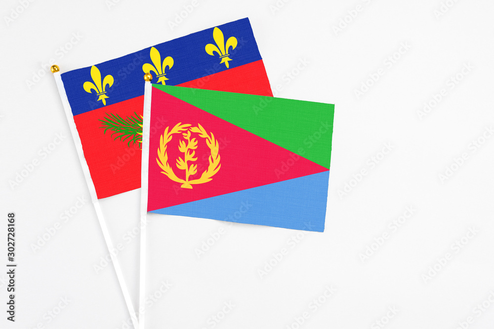 Eritrea and Guadeloupe stick flags on white background. High quality fabric, miniature national flag. Peaceful global concept.White floor for copy space. Eritrea and Guadeloupe stick flags on white background. High quality fabric, miniature national flag. Peaceful global concept.White floor for copy space.