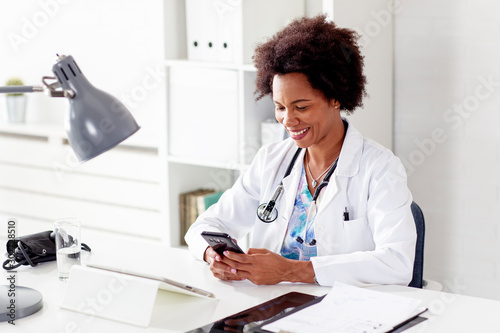 Woman doctor sitting at desk in ambulance and type text on mobile phone photo