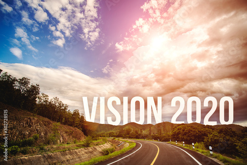 The word vision 2020 behind the tree of empty asphalt road at golden sunset and beautiful blue sky. Concept for vision year 2020. 