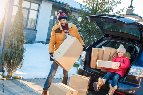 Moving to new apartment. Family together outdoors standing near car holding boxes smiling excited