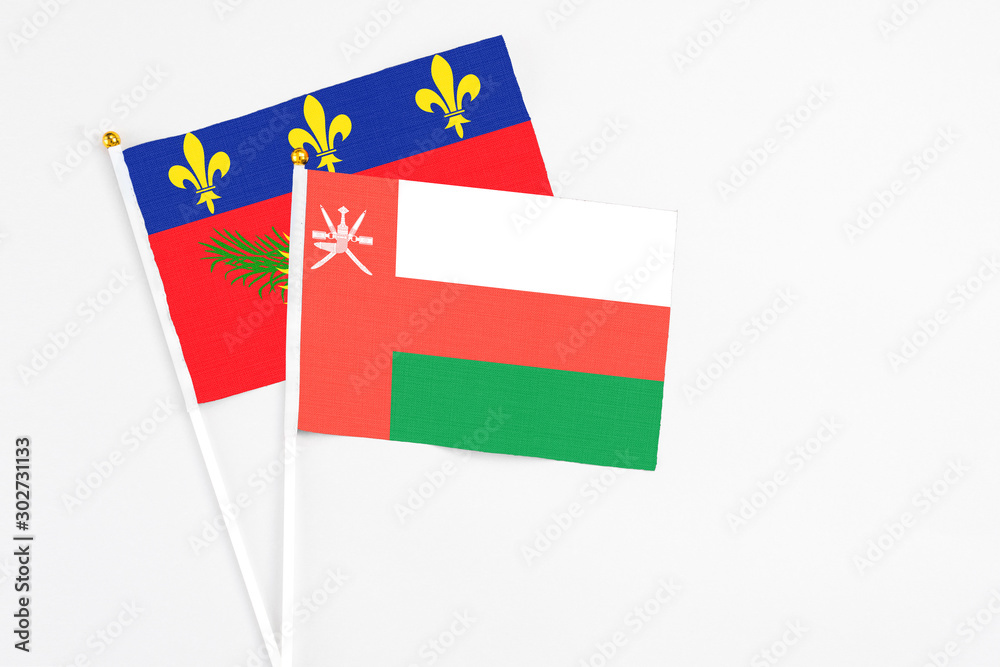 Oman and Guadeloupe stick flags on white background. High quality fabric, miniature national flag. Peaceful global concept.White floor for copy space. Oman and Guadeloupe stick flags on white background. High quality fabric, miniature national flag. Peaceful global concept.White floor for copy space.