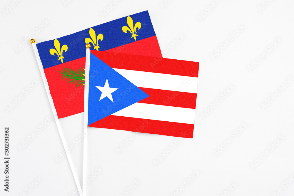 Obraz premium Puerto Rico and Guadeloupe stick flags on white background. High quality fabric, miniature national flag. Peaceful global concept.White floor for copy space.