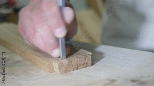 a joiner in an apron cuts a dovetail joint