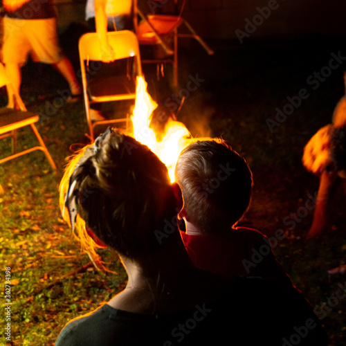 Family and Friends Sit Around a Backyard Fire Pit and Toast Smores