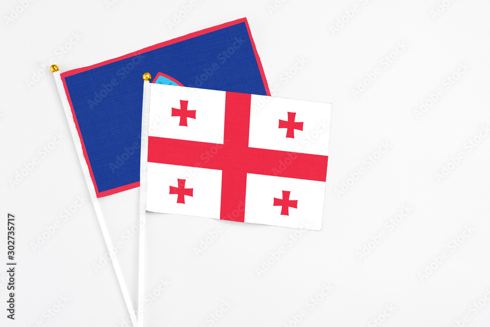 Georgia and Guam stick flags on white background. High quality fabric, miniature national flag. Peaceful global concept.White floor for copy space.