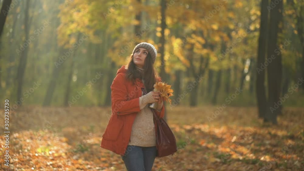 woman in orange jacket holding fallen leaves and thermos at in autumn park woman in orange jacket holding fallen leaves and thermos at in autumn park