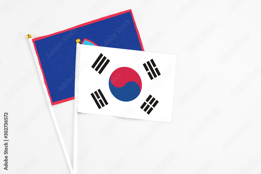 South Korea and Guam stick flags on white background. High quality fabric, miniature national flag. Peaceful global concept.White floor for copy space.