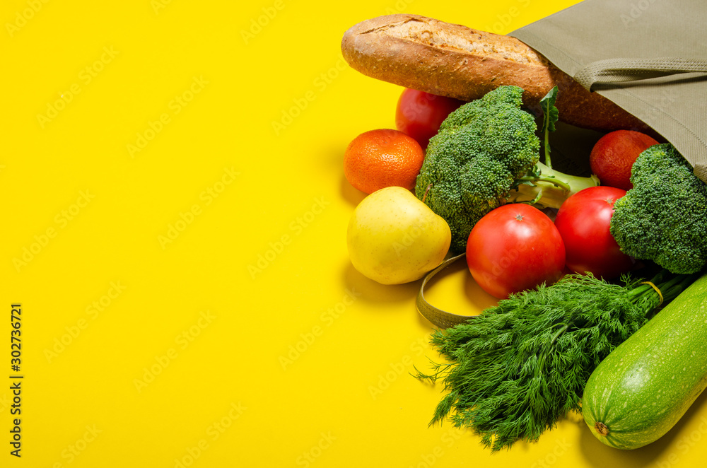 Food vegetable, bread, fruit in eco grocery bag on yellow background, top view - obrazy, fototapety, plakaty 