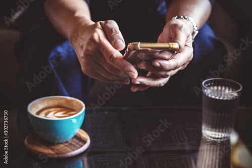 businessman using smartphone to read news and information of investment and reply email to confirm meeting in the coffee shop. man drinking hot latte coffee before going to work on monday morning.