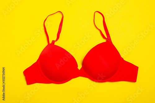 Red push up bra on yellow background, top view