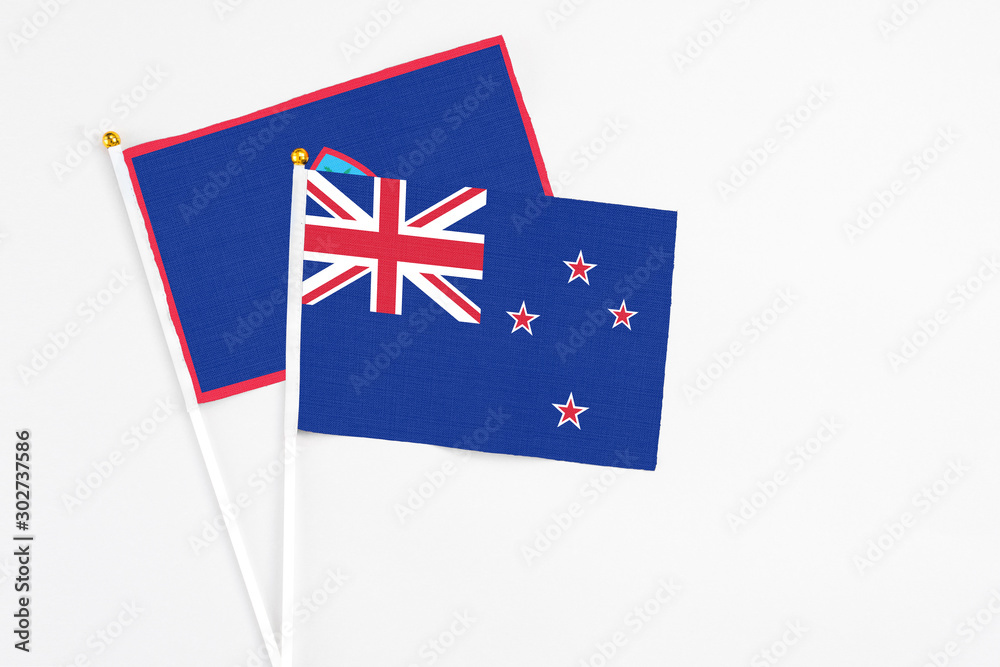 Fototapeta premium New Zealand and Guam stick flags on white background. High quality fabric, miniature national flag. Peaceful global concept.White floor for copy space.