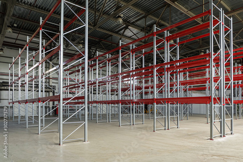 Empty multi-story shelving in industrial warehouse building. Rows of racks.