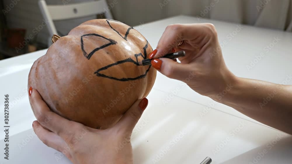 Drawing a funny face on a pumpkin with a black marker.draw halloween pumpkin ready to carving Drawing a funny face on a pumpkin with a black marker.draw halloween pumpkin ready to carving