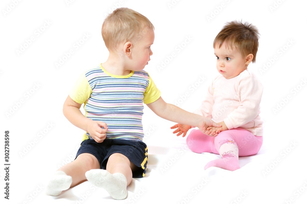 Two cute little children sitting and playing. Brother and sister with toy. Happy childhood. Light background Two cute little children sitting and playing. Brother and sister with toy. Happy childhood. Light background