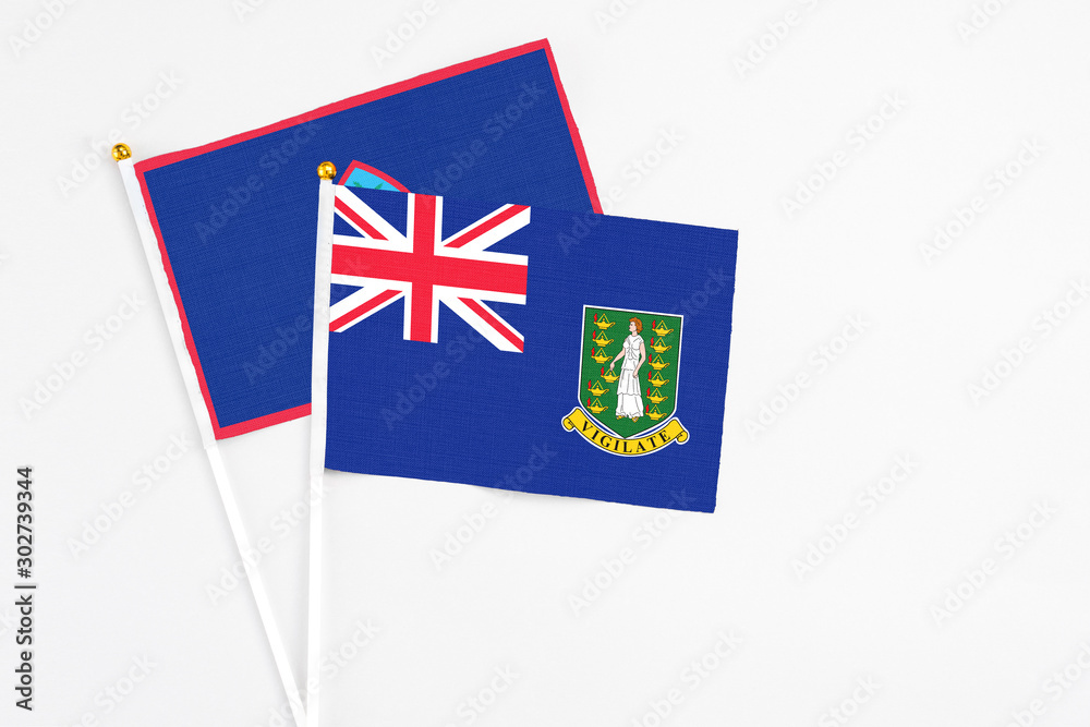 Fototapeta premium British Virgin Islands and Guam stick flags on white background. High quality fabric, miniature national flag. Peaceful global concept.White floor for copy space.