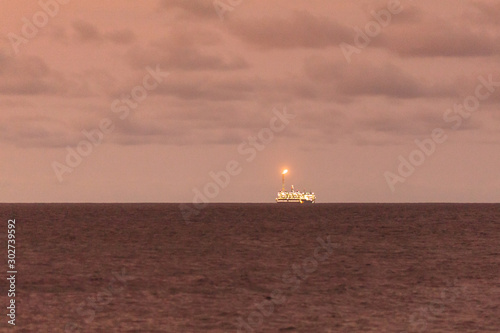 Sunset view, from the shore, of distant FLNG (Floating Liquefied Natural Gas) © Pvince73