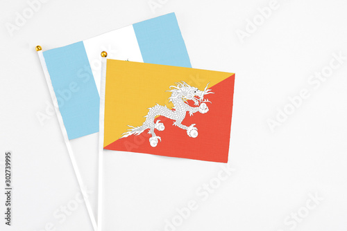Bhutan and Guatemala stick flags on white background. High quality fabric, miniature national flag. Peaceful global concept.White floor for copy space.