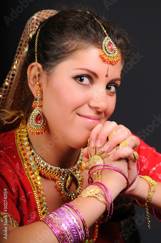 Portrait of beautiful caucasian white woman in traditional indian costume, interlocking fingers on dark background
