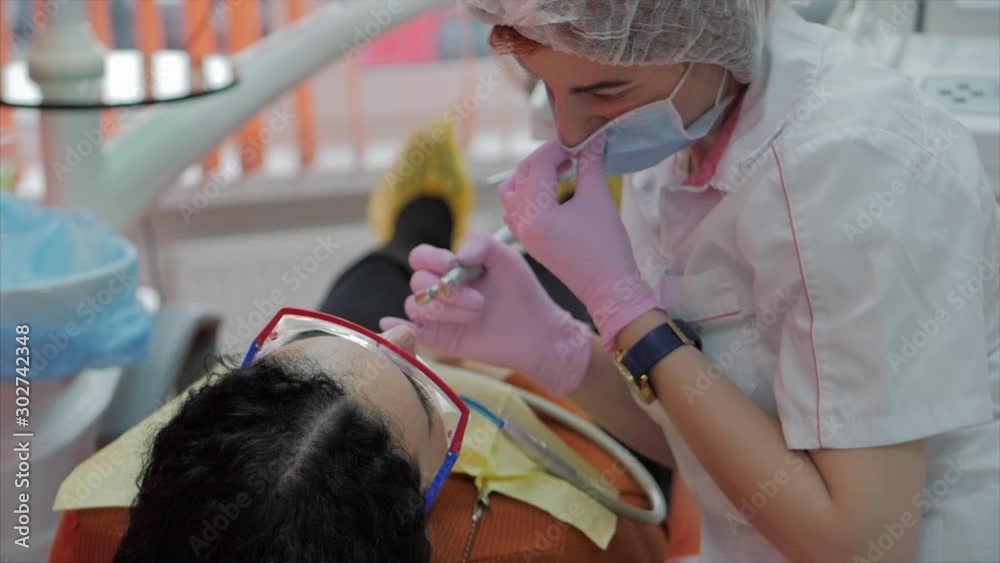 Woman Dentist Treating Teeth to Woman Patient in Clinic. Female Professional Doctor Stomatologist at Work. Concept Dental Check Up. Woman Dentist Treating Teeth to Woman Patient in Clinic. Female Professional Doctor Stomatologist at Work. Concept Dental Check Up.