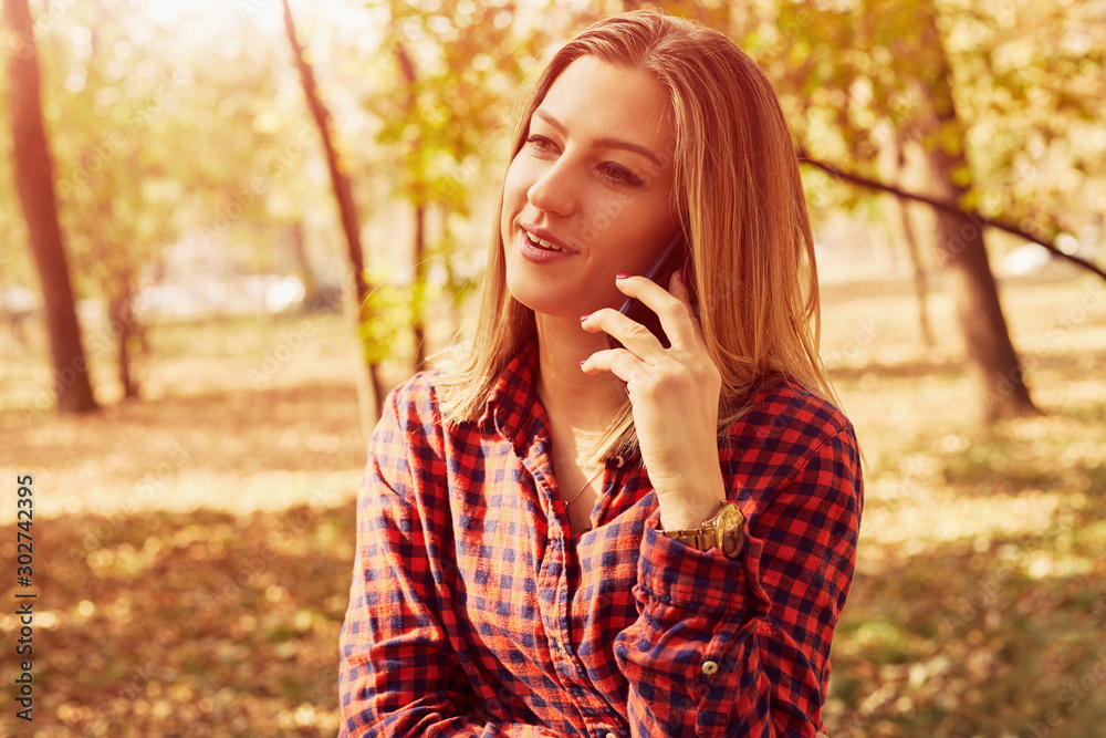 Attractive woman talking on her cellphone and enjoying in autumn day.	