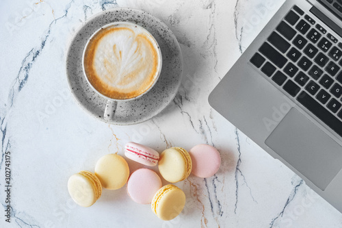 Worspace. Laptop cup of hot coffee and macarons close-up top view photo