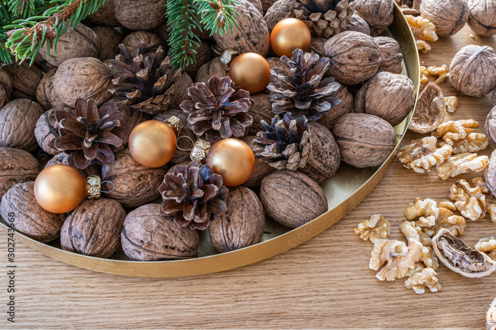 Merry Christmas decoration with walnuts on a natural oak wooden background. A natural perspective composition in brown and gold colors. Merry Christmas decoration with walnuts on a natural oak wooden background. A natural perspective composition in brown and gold colors.